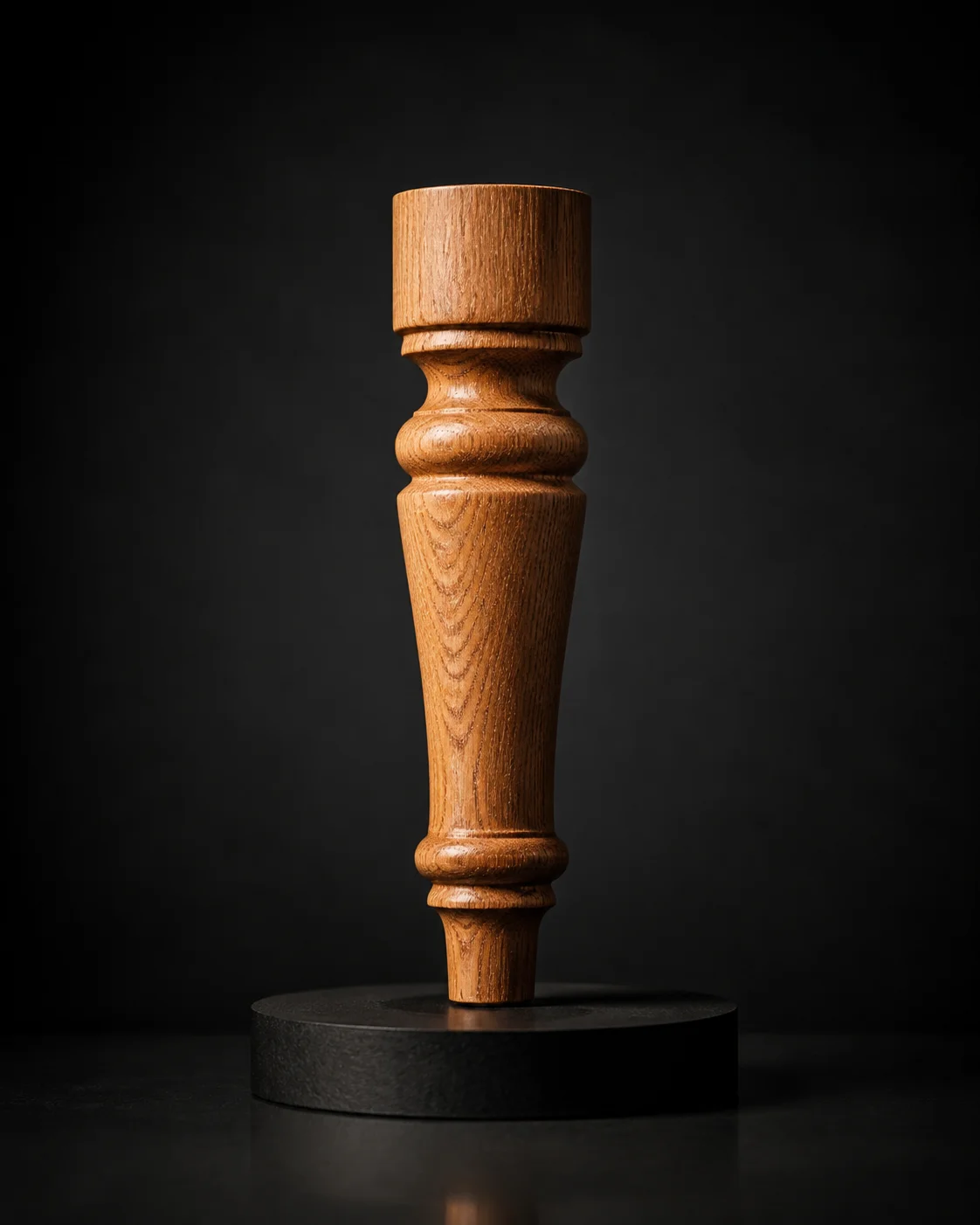 Turned oak furniture leg standing on a black pedestal